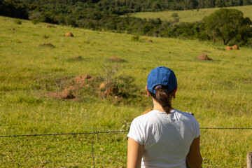 Girl from the back looking at the landscape in blue cap and white t-shirt.