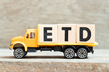 Toy truck hold alphabet letter block in word ETD (abbreviation of estimated time of departure or the estimated time of delivery) on wood background