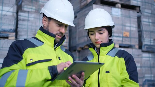 Follow footage of employees male and famale warehouse worker engineer in hard hat working. walking through logistics center warehouse factory construction site logistics architect businessman man