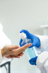 Epidemiological researchers in virus protective clothing washing hands with alcohol gel before beginning the experiment in a scientific laboratory. Hygiene concept.