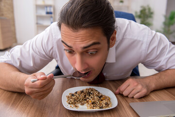 Hungry male employee eating buckwheat during break