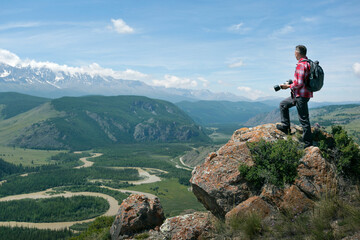  Man Traveler With Backpack Taking Photo On Top Of Mountain. Travel and active lifestyle concept.