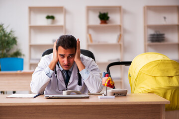 Young male doctor looking after new born in the clinic