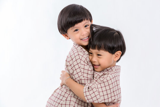 Twin boys hugging  on white background. Portrait of little son hugging brother or friend. I missing you. Full length happy boy embracing glad brother or friend while standing indoor. Positive meeting 