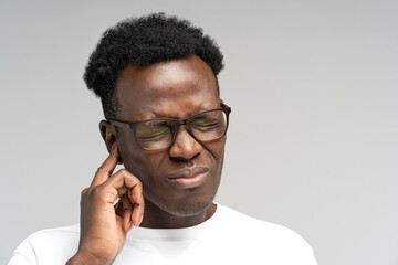 Sick African American millennial man suffering from tinnitus, throbbing earache, tired of noise....