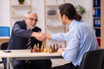 Two businessmen playing chess in the office