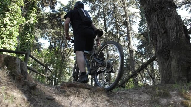 young man rides mountain bike in forest trail 
