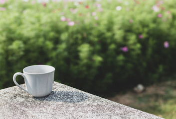 A selective focus picture of a cup of coffee on stone table in green garden