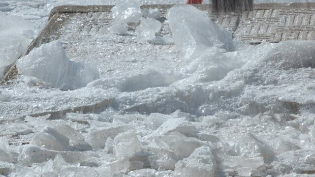 Cleaning of paving slabs from ice with a metal ice pick or crowbar. The work of public services on the street of the city close-up. 4K video. Lower angle.