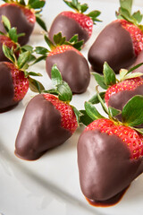 chocolate covered strawberries on a white plate on a marble table. excellent gift for mother's day.