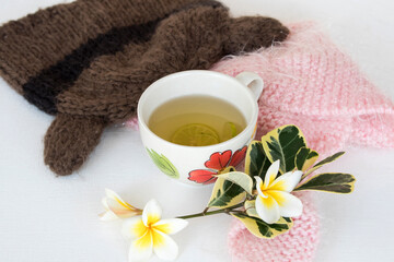 herbal healthy drinks hot honey lemon health care for cough sore with flowers frangipani, knitting wool arrangement flat lay style on background white wooden
