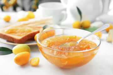 Fototapeta na wymiar Delicious kumquat jam in glass bowl on white table, closeup