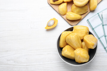 Delicious exotic jackfruit bulbs on white wooden table, flat lay. Space for text