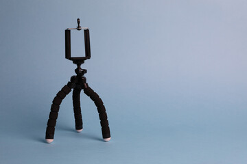 Modern stylish mobile tripod on light blue background. Space for text