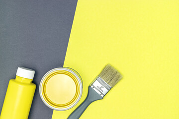 yellow paint cans and paintbrush on yellow and gray background. top view