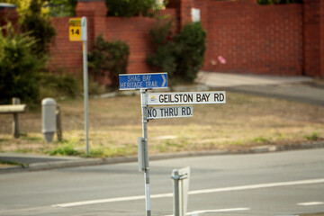 View from a long distance away of a street sign, with a a bus stop sign in the background