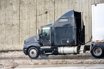 Geometric profile of black big rig semi truck tractor with dry van semi trailer running on the...