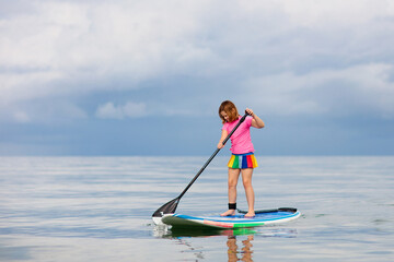 Child on stand up paddle. Water and beach sport