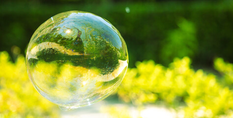 A large soap bubble flies in the park.