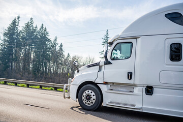 White industrial professional big rig semi truck tractor with high cab for long haul running on the sunny highway road