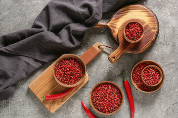 Bowls with red peppercorns on grey background