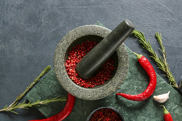 Mortar and pestle with red peppercorns on dark background