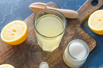 Fresh lemons and glass of juice on color background