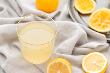 Fresh lemons and glass of juice on fabric background