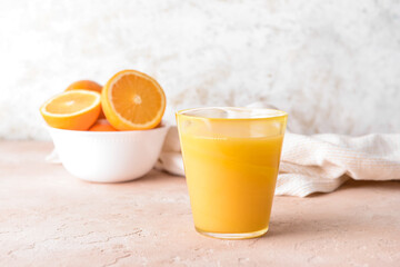 Fresh oranges and glass of juice on color background