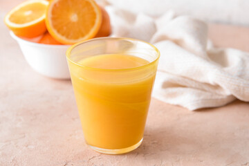 Fresh oranges and glass of juice on color background