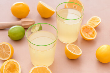 Fresh lemons and glasses of juice on color background