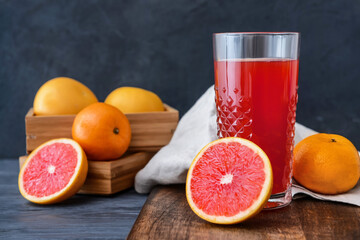 Fresh grapefruits and glass of juice on color background