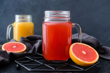 Mason jars of orange and grapefruit juice on dark background