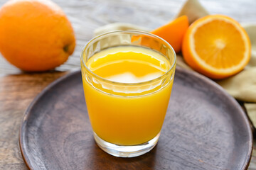 Glass of orange juice on wooden background