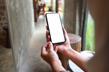 Mockup image of a woman holding mobile phone with blank white desktop screen