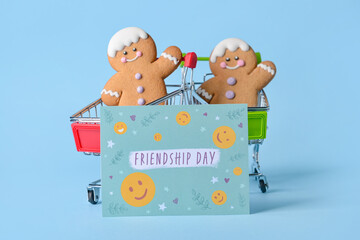Shopping carts with cookies and greeting card for Friendship Day on color background