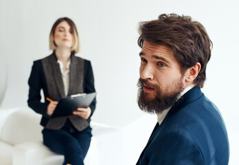 Fototapeta na wymiar Business woman In a bright room and an upset man with a beard in the foreground is job interview