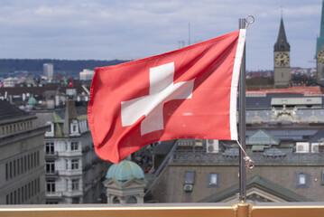 Swiss flag flowing in the wind on gondola of ferris wheel at city of Zurich, Switzerland, at springtime.