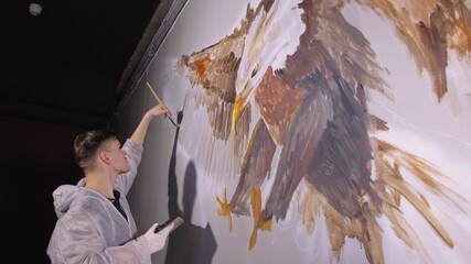 Artist designer draws an eagle on wall. Craftsman decorator paints picture with acrylic oil color...