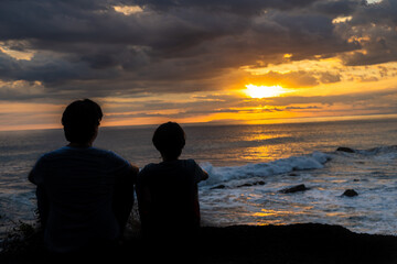 Beautiful picture of Father and son  watching the sunset in the pacific ocean in the magical beaches of Costa Rica