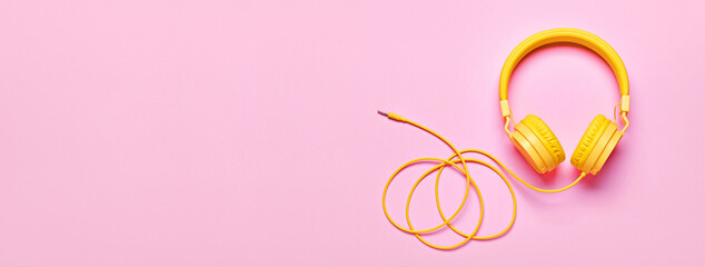 Yellow headphones on pink banner. Minimal Music concept, flat lay, copy space