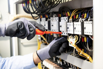 Electricians work to connect electric wires in the system, switchboard, electrical system in...