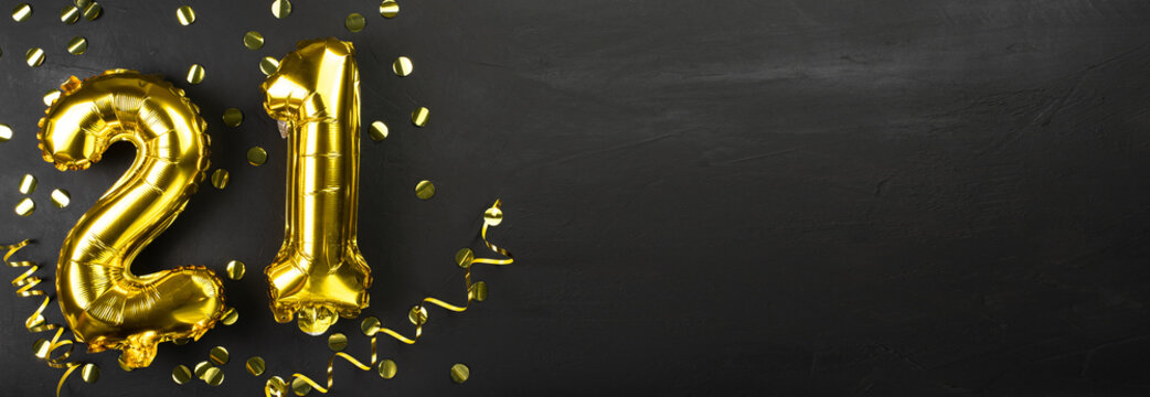 gold foil balloon number twenty one. Birthday or anniversary greeting card with the inscription 21. Black concrete background. Anniversary celebration. Banner.