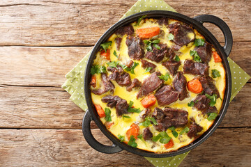 Balsica tava spicy beef with vegetables baked with eggs, sour cream and milk close-up in a frying pan on the table. horizontal top view from above