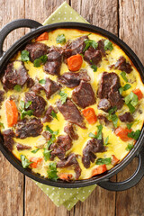 Montenegrin cuisine boiled and then baked beef with egg-milk sauce close-up in a frying pan on the table. vertical top view from above