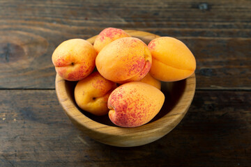 Fresh apricots in a wooden plate.
