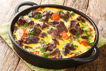 Balsica tava spicy beef with vegetables baked with eggs, sour cream and milk close-up in a frying pan on the table. horizontal