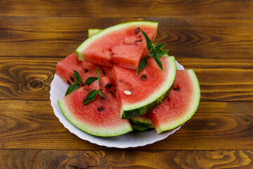 Fresh ripe sliced watermelon in white plate on a wooden table