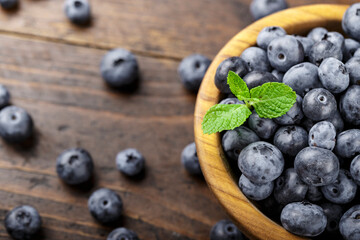 Freshly picked blueberries in wooden bowl on a wooden  table.