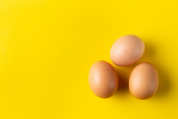 Three chicken egg  isolated on yellow. Top view with copy space.